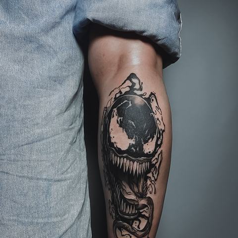 An ornamental forearm tattoo with a dark central motif, layered decorative elements and flowing blackwork details.