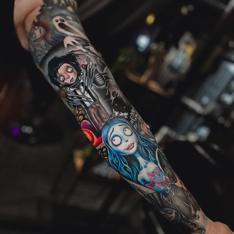 A vivid full-sleeve tattoo with layered ornamental motifs, deep black shading and striking blue and red highlights.