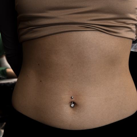 Stylish navel piercing with minimalist jewellery that highlights the midsection and adds a refined detail to the overall look.