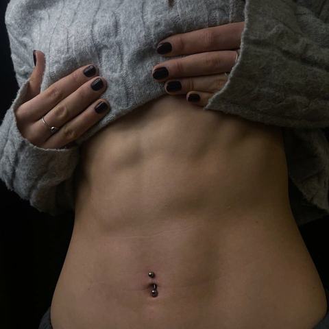 Elegant navel piercing with delicate jewellery that enhances the body line and brings a stylish, polished touch to the overall look.