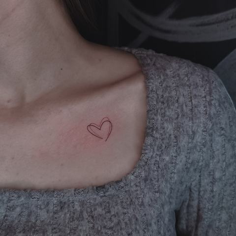 Neliels minimālistisks sirds tetovējums pie atslēgas kaula ar smalku līniju un vieglu, lakonisku dizainu.