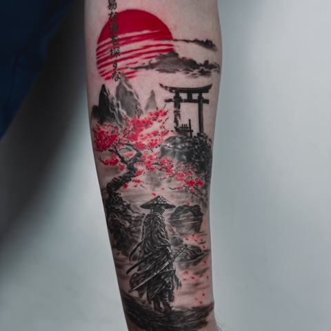 A Japanese-inspired forearm tattoo with a red sun, architectural elements and detailed black shading.
