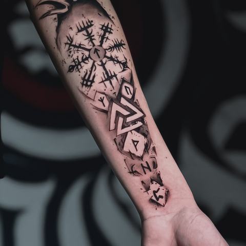 Grafisks tetovējums uz apakšdelma ar ģeometriskiem un ornamentāliem motīviem, izteiktām melnām līnijām un vertikālu kompozīciju.