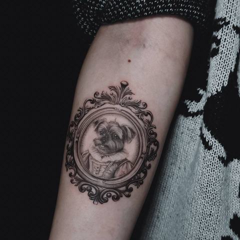 An ornamental forearm tattoo with a compass-inspired centre, fine geometric details and balanced black shading.