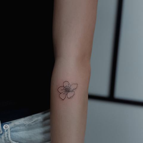 A tiny fine-line forearm tattoo with two delicate cherries and a simple, playful composition.
