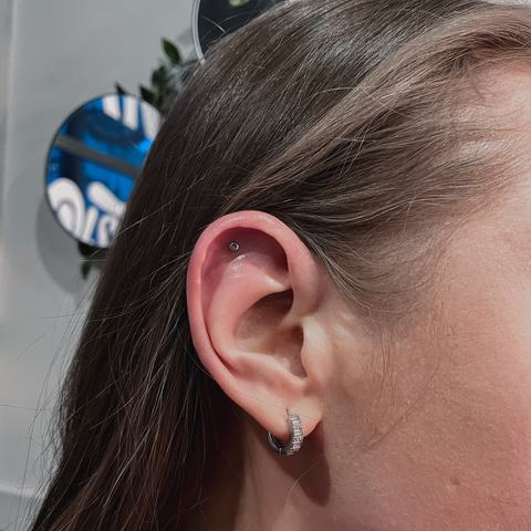 Helix and lobe piercings with coordinated jewellery that create a clean, balanced and modern ear composition.