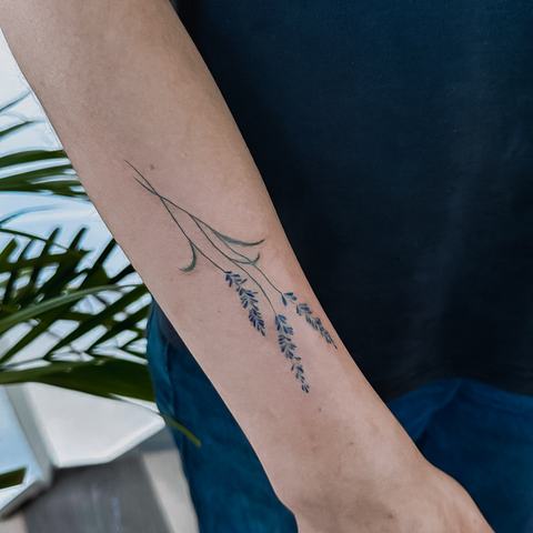 Delicate wrist tattoo with fine ornamental lines, subtle symmetry and a graceful vertical composition.
