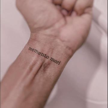 Small Memento Mori lettering tattoo on wrist