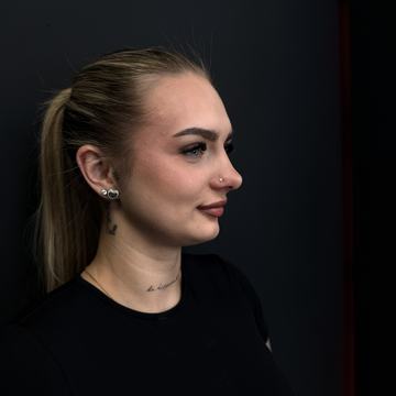 Sieviete ar sejas pīrsingu sānskatā.